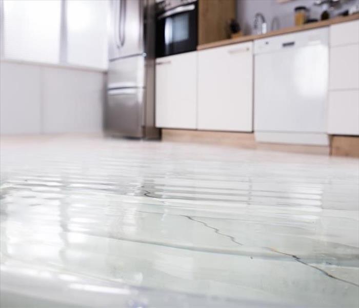 Bright kitchen with white tiled floor covered in a sheet of rippling water